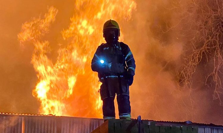 Road closed as dozens of firefighters battle major blaze at timber yard