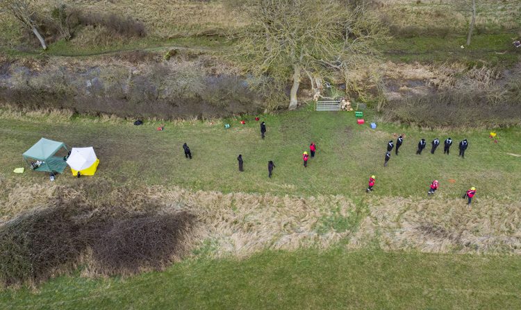 Specialist police officers and search volunteers line former canal