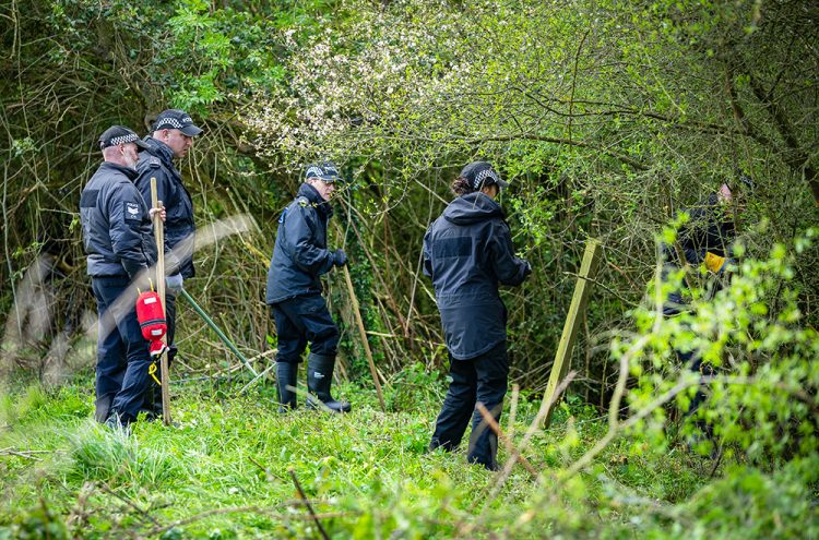 Police officers strim bushes and search alpaca farm in Wiltshire