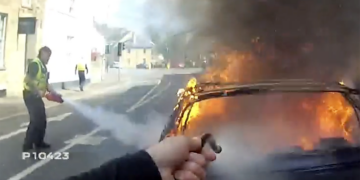 Police officers tackle raging car blaze using only fire extinguishers