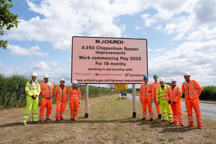 A group of people in hi-viz clothing and hard hats. In between them is a sign that reads MJ Church A 350 Chippenham Bypass Improvements Work commencing May 2025 For 18 months Working in partnership with Wiltshire Council, Department for Transport, Atkins Realis and then the web address wiltshire.gov.uk/highways-improvements