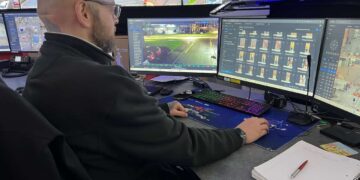 A man looking at a bank of CCTV monitors