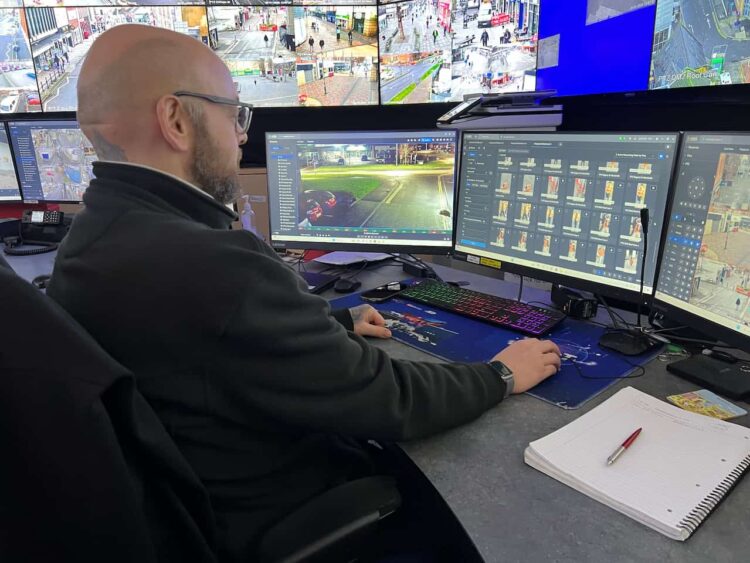 A man looking at a bank of CCTV monitors