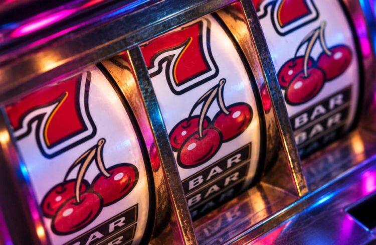 Classic fruit slot machine reels with cherries, red sevens and BAR symbols under colorful neon lighting
